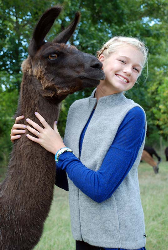 Girl modeling grey alpaca vest with llama
